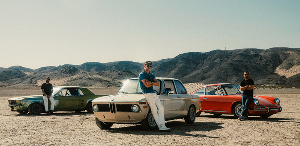 man standing on car siter wearing aviator sunglasses