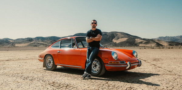 man standing near a red car wearing aviator sunglasses