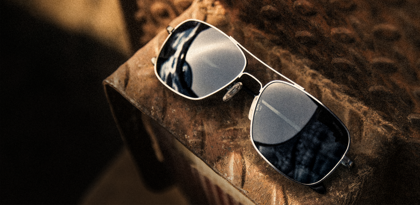 RANDOLPH Frontier sunglasses in Satin Gunmetal Finish with Slate mirrored lenses on a workbench.